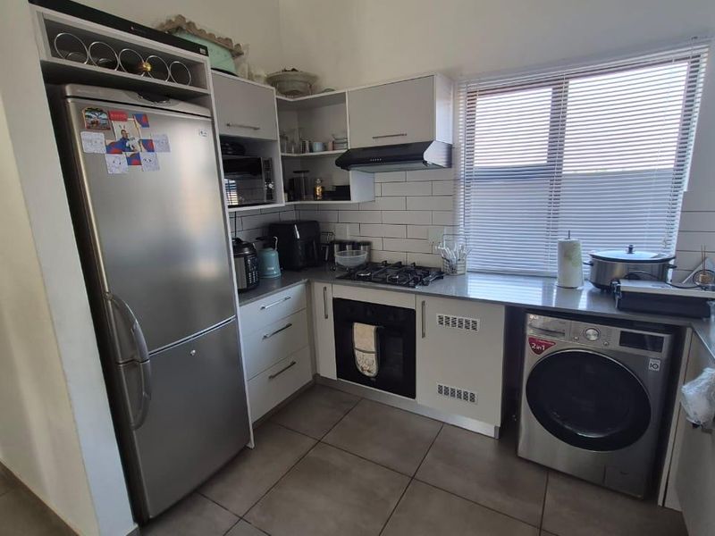 A functional kitchen featuring white cabinetry, subway tile backsplash, gas hob, built-in oven, and integrated laundry appliance space with tiled flooring.