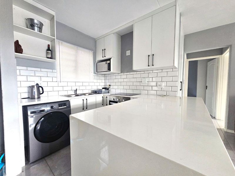 Modern kitchen featuring white cabinetry, subway tile backsplash, quartz countertops, and integrated appliances, offering a clean and functional workspace.