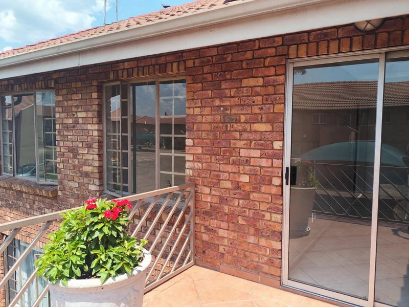 A private balcony featuring face brick exterior walls, tiled flooring, and a secure sliding glass door entrance.
