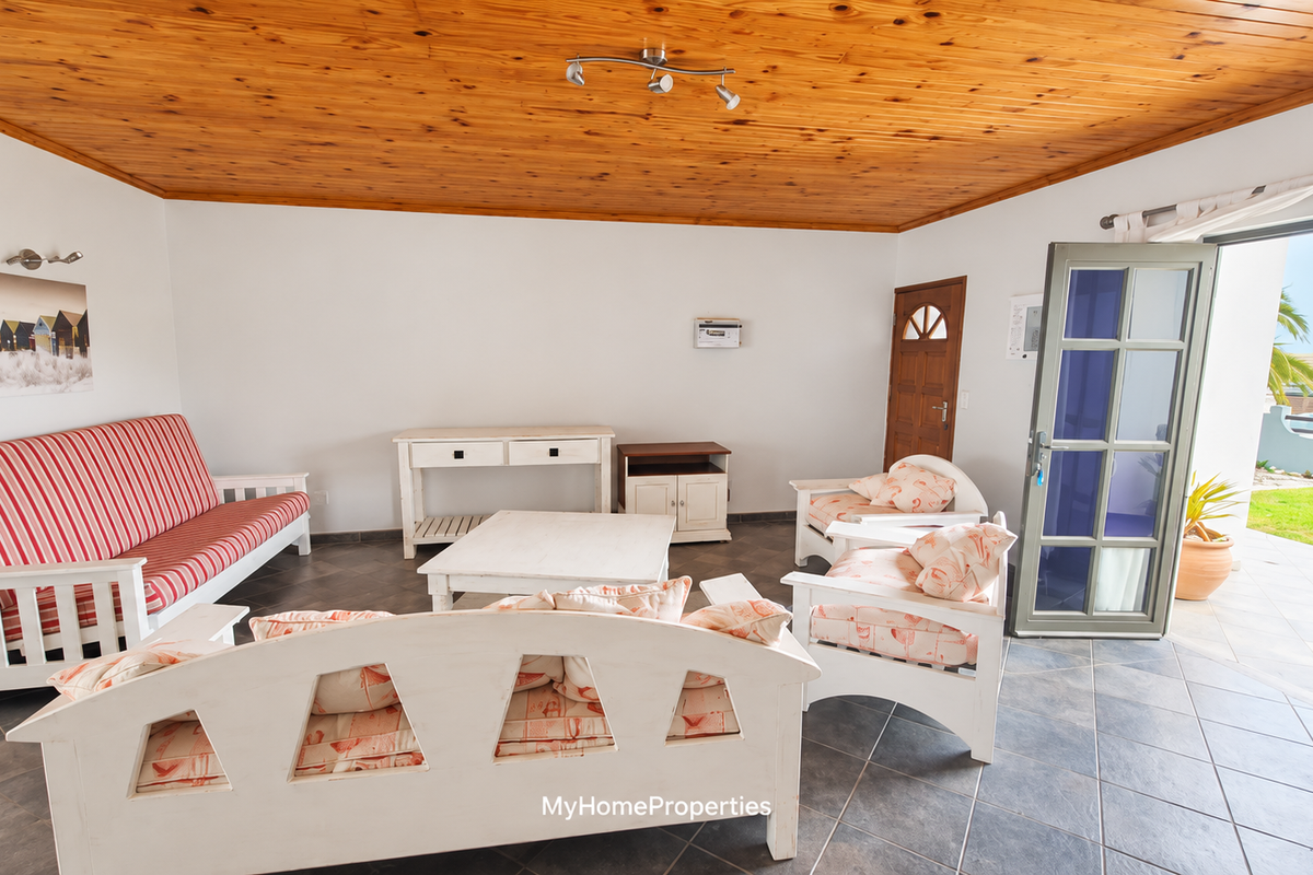 A living room featuring a timber ceiling, tiled flooring, and direct access to an outdoor patio area through a glass-paneled door.