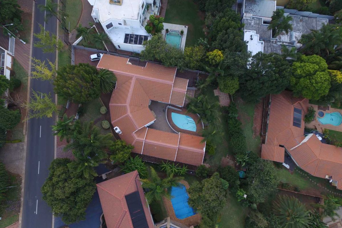 Aerial view of the property showcasing the tiled roof structure, private swimming pool, and surrounding landscaped garden area.