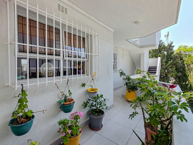 A clean, tiled balcony area featuring security bars on the windows and access to an external staircase.