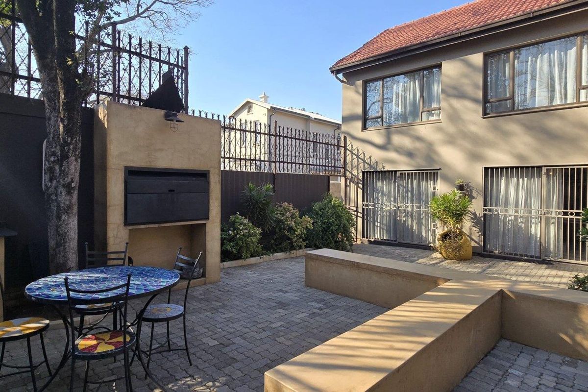 A private rear courtyard featuring a paved patio, built-in braai, and integrated concrete seating, providing a functional outdoor entertainment space.