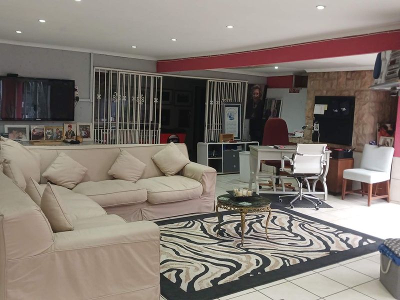 Spacious open-plan living area featuring tiled flooring, recessed lighting, and a stone feature wall, offering a versatile layout for relaxation and home office use.