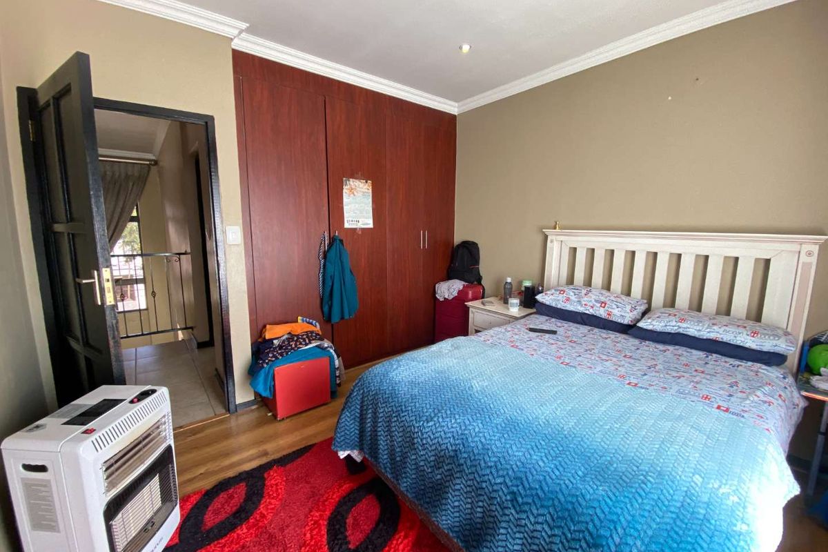 A bedroom featuring laminate flooring, built-in cupboards, and coving detail, providing a functional space with direct access to an adjacent hallway.
