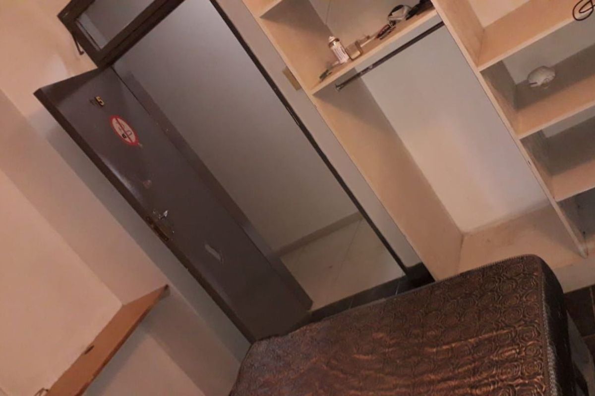 A bedroom interior featuring built-in shelving and a doorway, showing signs of wear and dated finishes.