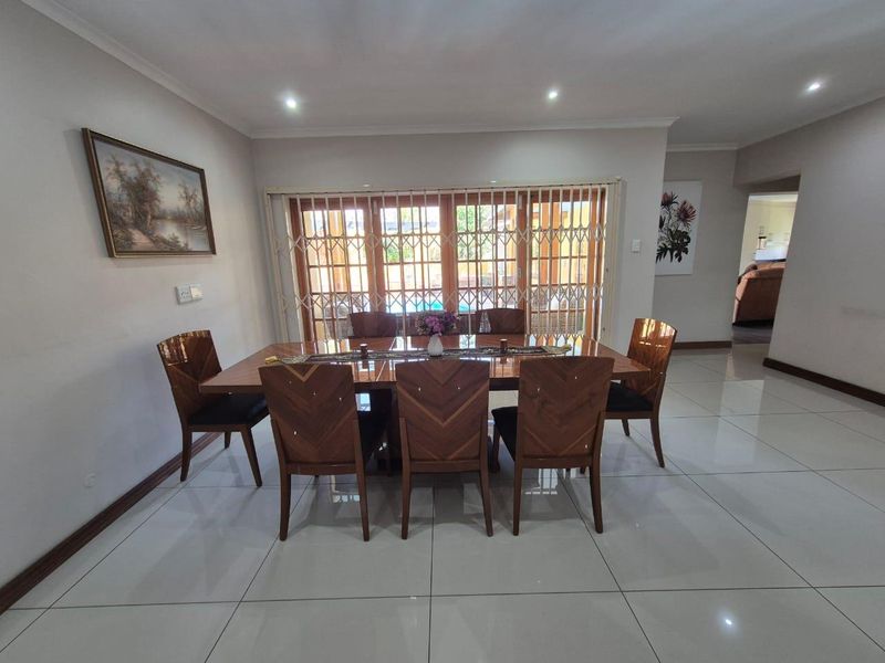 Spacious dining room featuring large format floor tiles, recessed downlighting, and sliding glass doors providing access to the outdoor area.