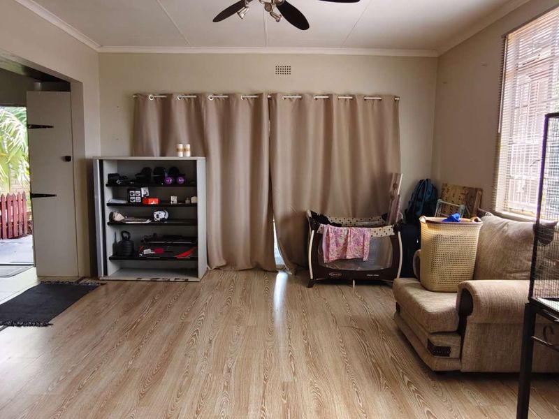 A living room featuring laminate flooring, a ceiling fan, and a sliding door providing access to an outdoor area.
