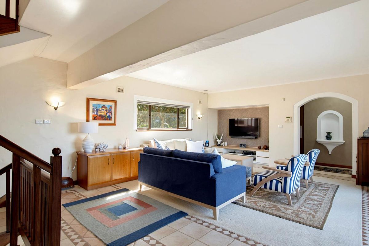 Spacious living room featuring tiled flooring, a built-in media console, and an elegant arched entryway leading to an adjacent space.