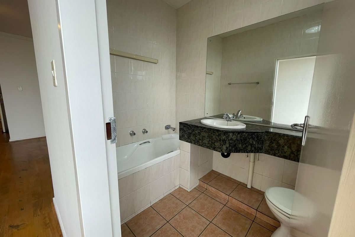 A functional bathroom featuring a built-in bathtub, a wall-mounted vanity with a granite countertop, and tiled flooring.