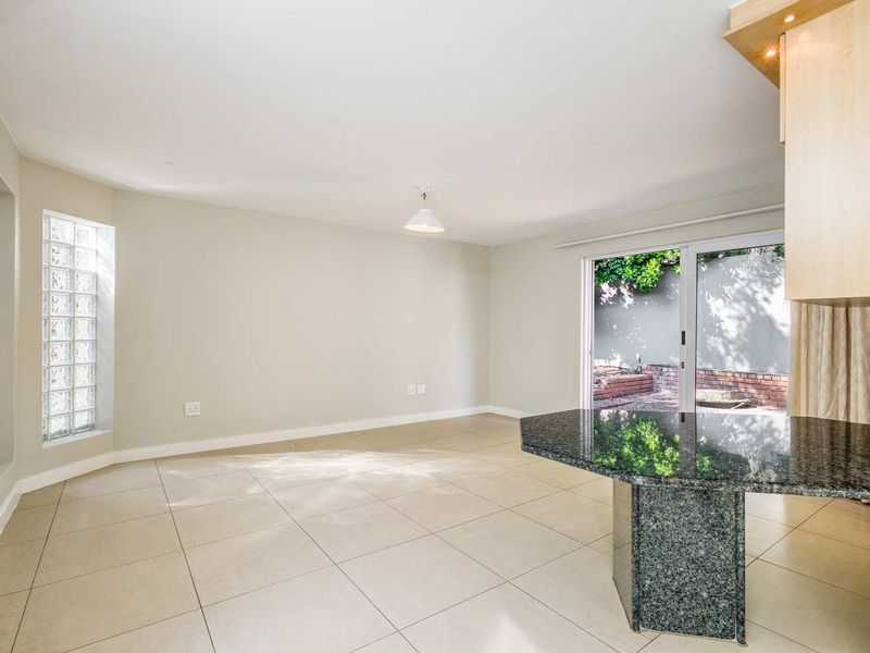 Spacious open-plan living area featuring tiled flooring, a granite breakfast bar, and a glass block window with direct access to the rear patio.
