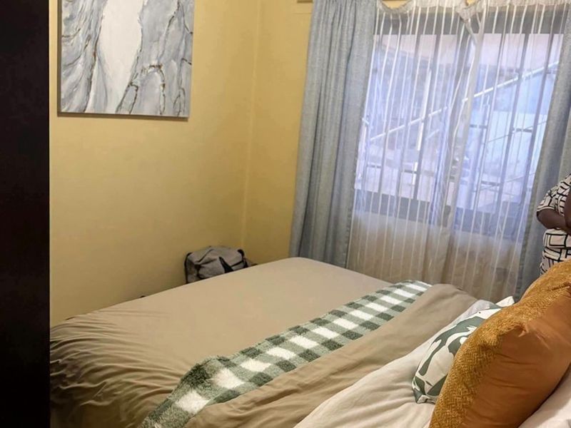 A standard bedroom featuring a window with installed curtain rods and neutral wall finishes.