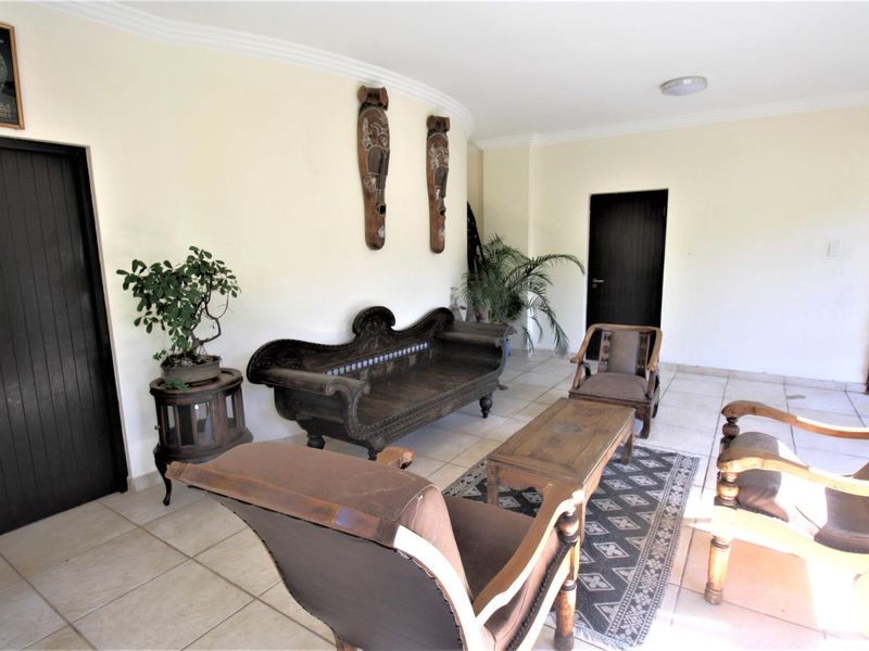 A spacious living area featuring neutral tiled flooring and coved ceiling details, providing a versatile foundation for interior design updates.