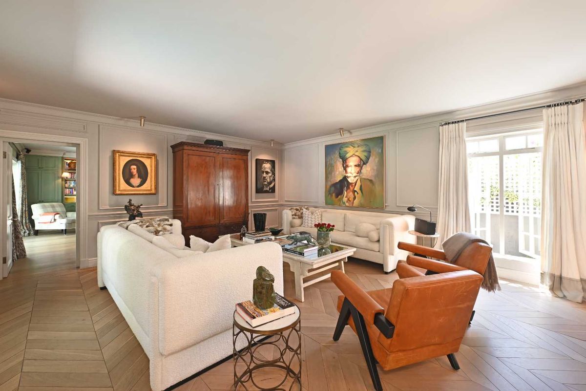 Elegant living room featuring sophisticated wall paneling, high-quality herringbone timber flooring, and large windows providing ample natural light.