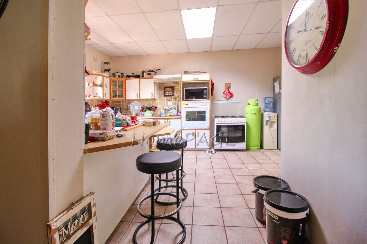 A functional kitchen featuring built-in cabinetry, a wall-mounted oven, and a gas stove, with a breakfast bar counter overlooking the space.