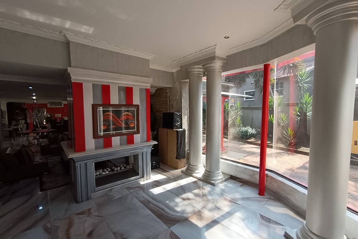 Spacious living area featuring decorative columns, large floor-to-ceiling windows, polished marble-style flooring, and a prominent fireplace with a unique red and grey striped feature wall.