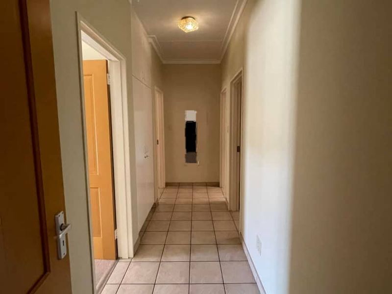 A functional hallway featuring neutral tiled flooring and access to multiple rooms, providing a clean and simple transition space within the townhouse.