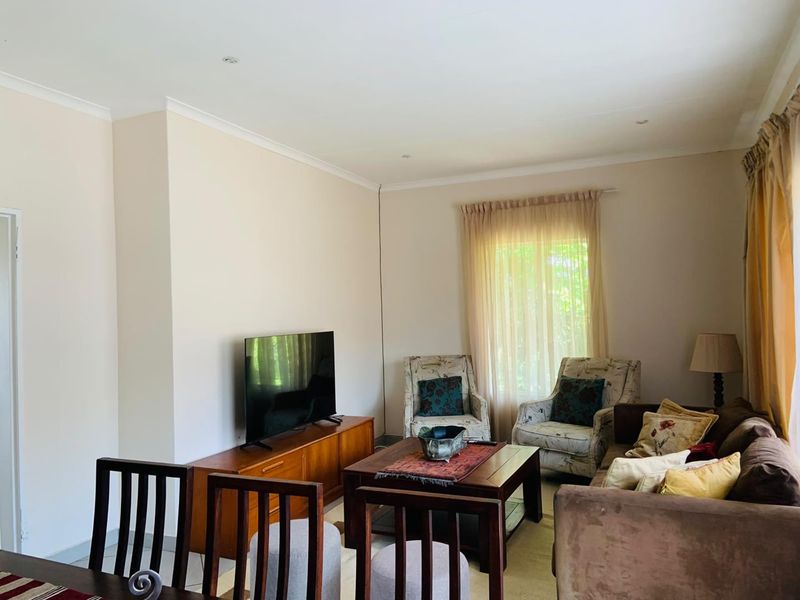 A comfortable living room featuring neutral wall finishes, recessed downlighting, and coved ceiling detailing, providing a functional and well-lit space.