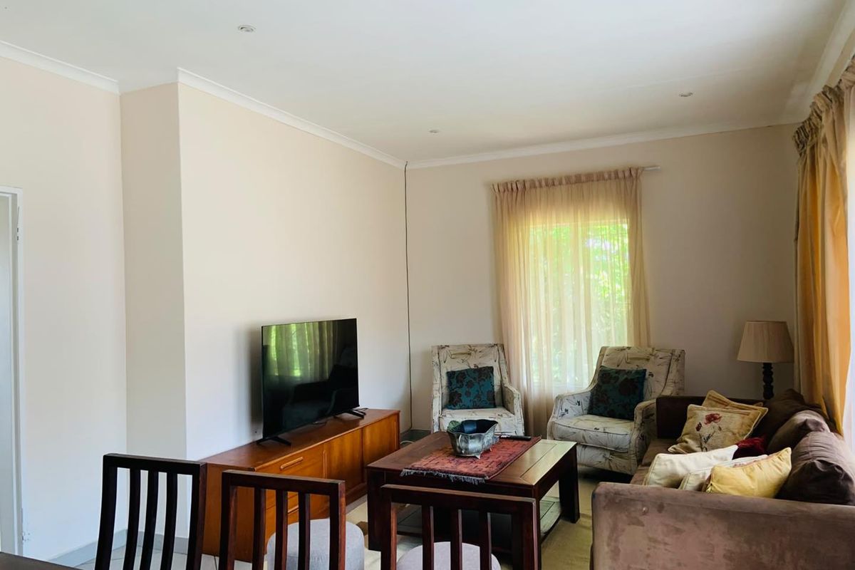 A comfortable living room featuring neutral wall finishes, recessed downlighting, and coved ceiling detailing, providing a functional and well-lit space.