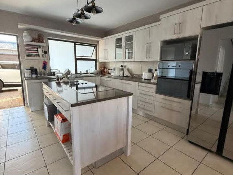 Modern kitchen featuring a central island, built-in oven and microwave, light-toned cabinetry, and tiled flooring with direct access to the exterior.