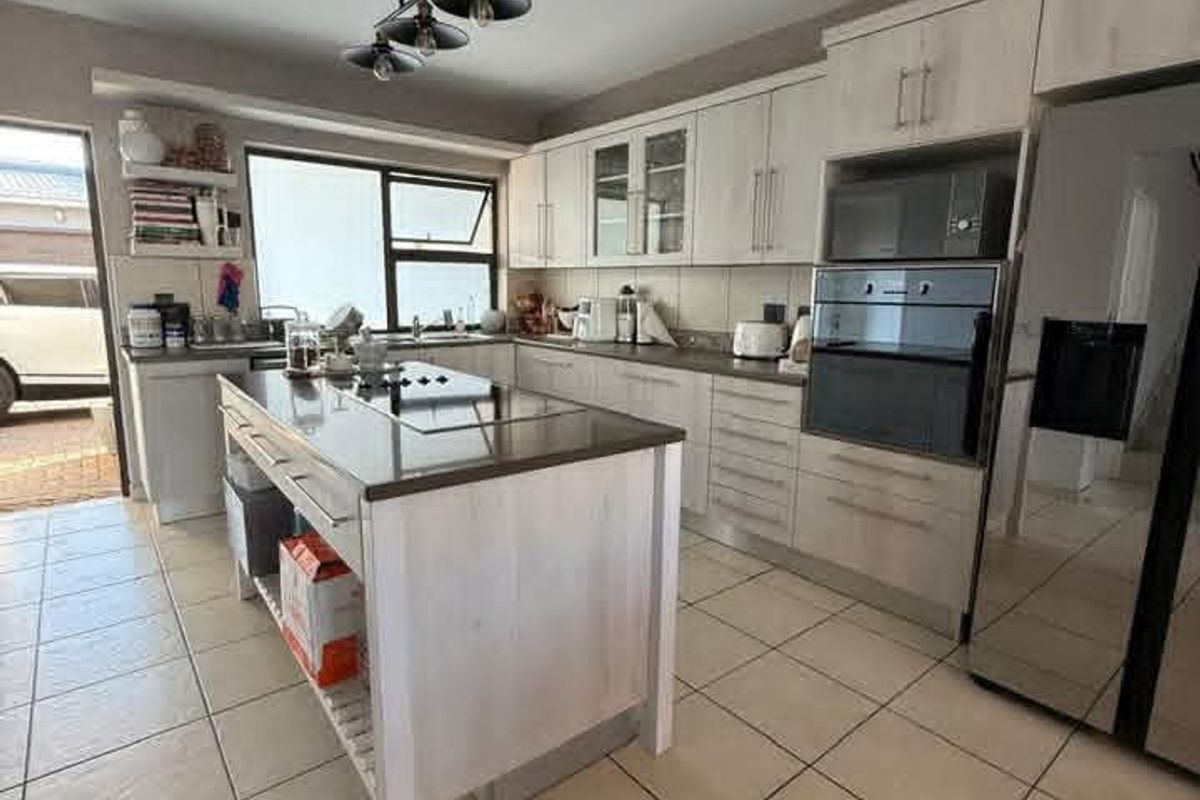 Modern kitchen featuring a central island, built-in oven and microwave, light-toned cabinetry, and tiled flooring with direct access to the exterior.