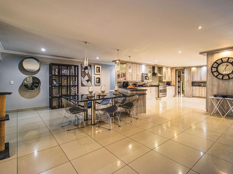 Spacious open-plan living and dining area featuring modern kitchen cabinetry, a central island, tiled flooring, and recessed lighting throughout.