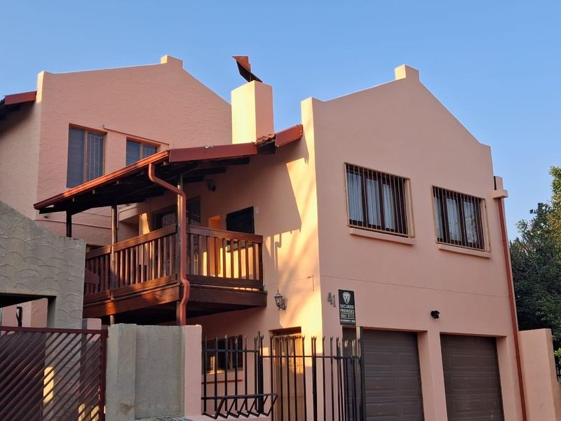 Front elevation of a two-story house featuring a double garage, a wooden balcony, and security bars on the windows.
