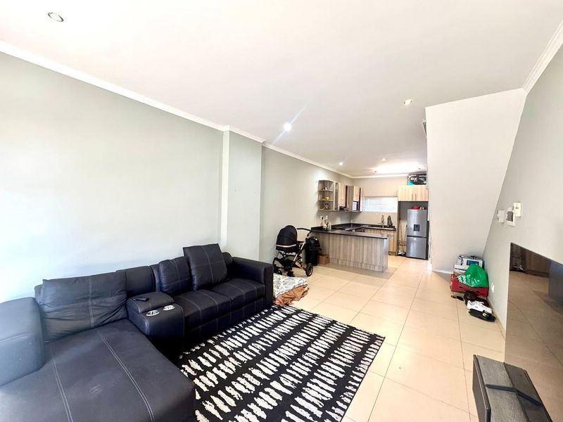 Open-plan living area featuring a kitchen with built-in cabinetry and island, flowing into a spacious lounge area with tiled flooring throughout.