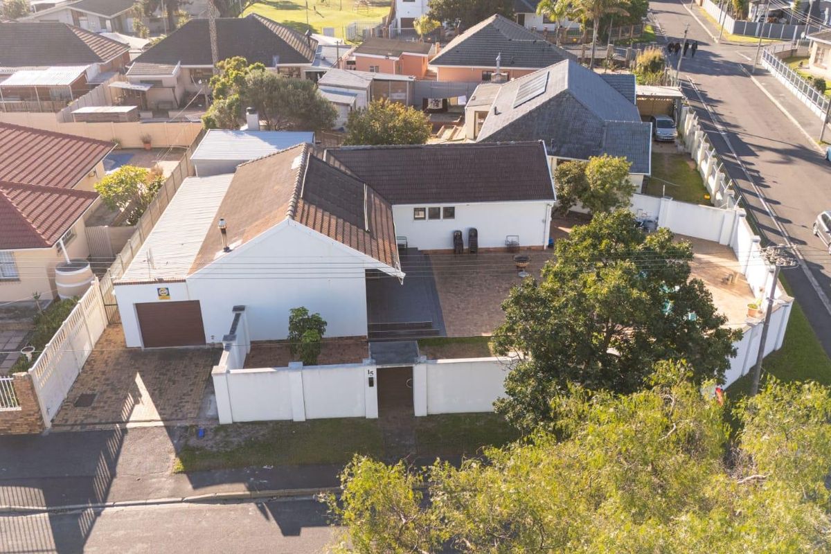 Aerial view of a residential property featuring a tiled roof, paved driveway, garage, and a private backyard with a swimming pool and patio area.