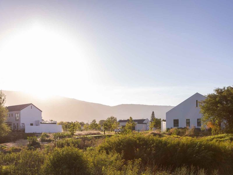 A scenic view of the residential estate featuring modern white homes set against a backdrop of mountains and natural landscape.