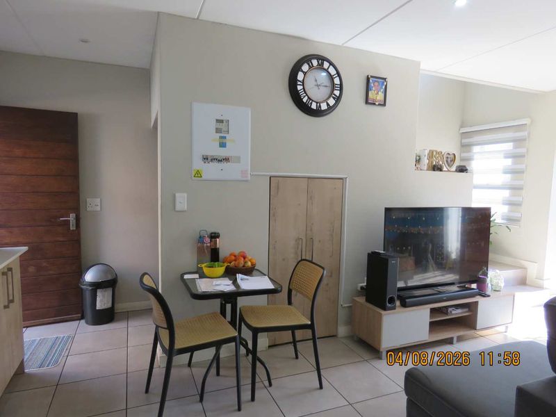 Open plan living area featuring tiled flooring, built-in storage, and a timber entrance door, providing a functional and connected living space.