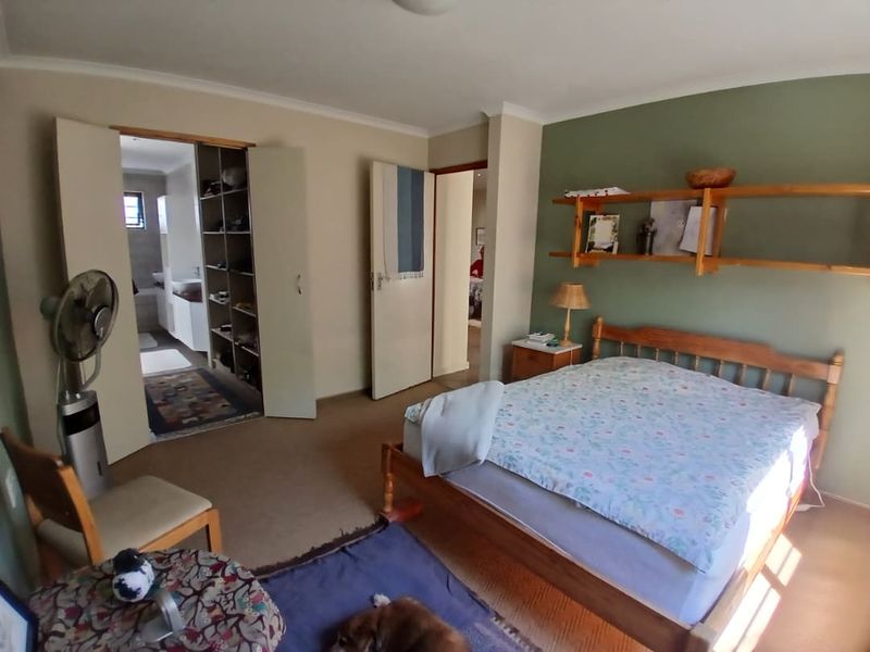 Spacious bedroom featuring built-in cupboards, wall-mounted shelving, and direct access to an en-suite bathroom.