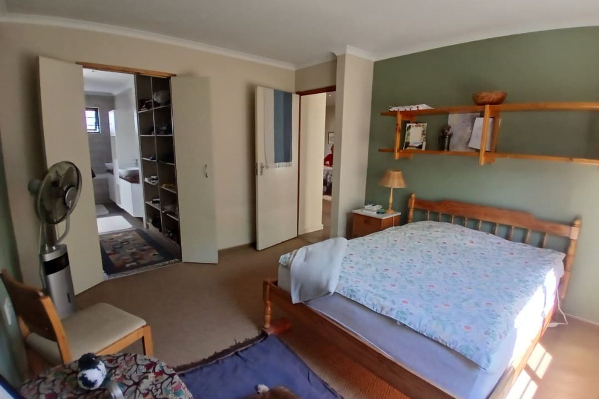 Spacious bedroom featuring built-in cupboards, wall-mounted shelving, and direct access to an en-suite bathroom.