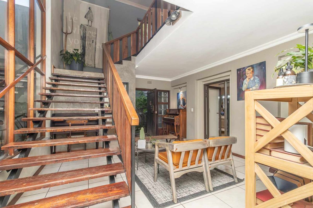 Spacious living area featuring an open-tread timber staircase, tiled flooring, and double-volume ceilings, creating an airy and architectural atmosphere.