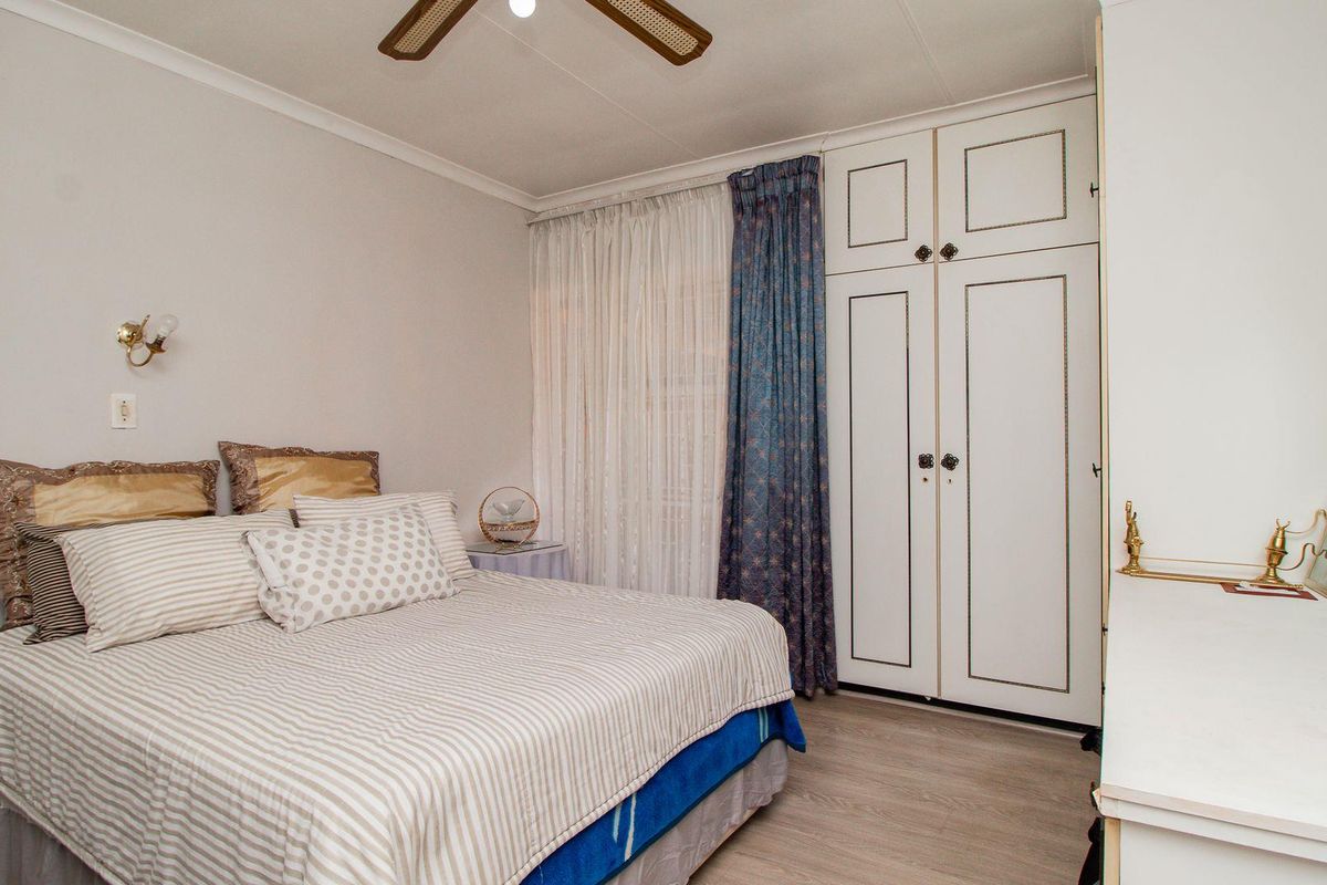 A well-maintained bedroom featuring built-in cabinetry, laminate flooring, and a ceiling fan, offering a functional and comfortable living space.