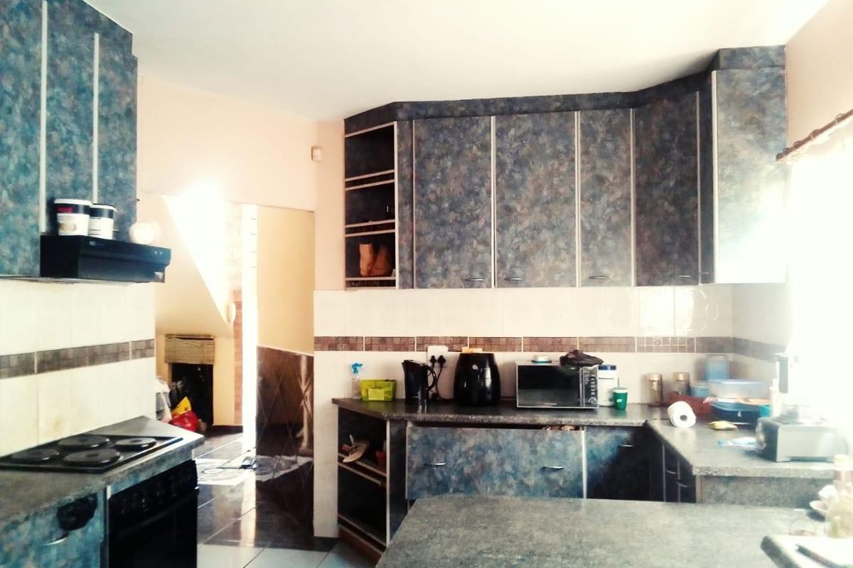 A functional kitchen featuring dated laminate cabinetry, tiled splashbacks, and built-in cooking appliances, offering potential for a modern renovation.