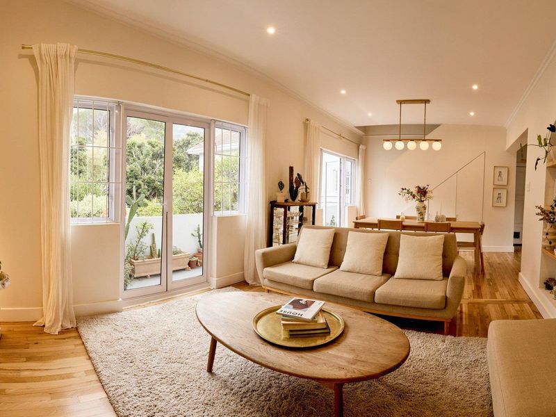 Bright open-plan living and dining area featuring hardwood flooring, recessed lighting, and sliding glass doors leading to an outdoor balcony.