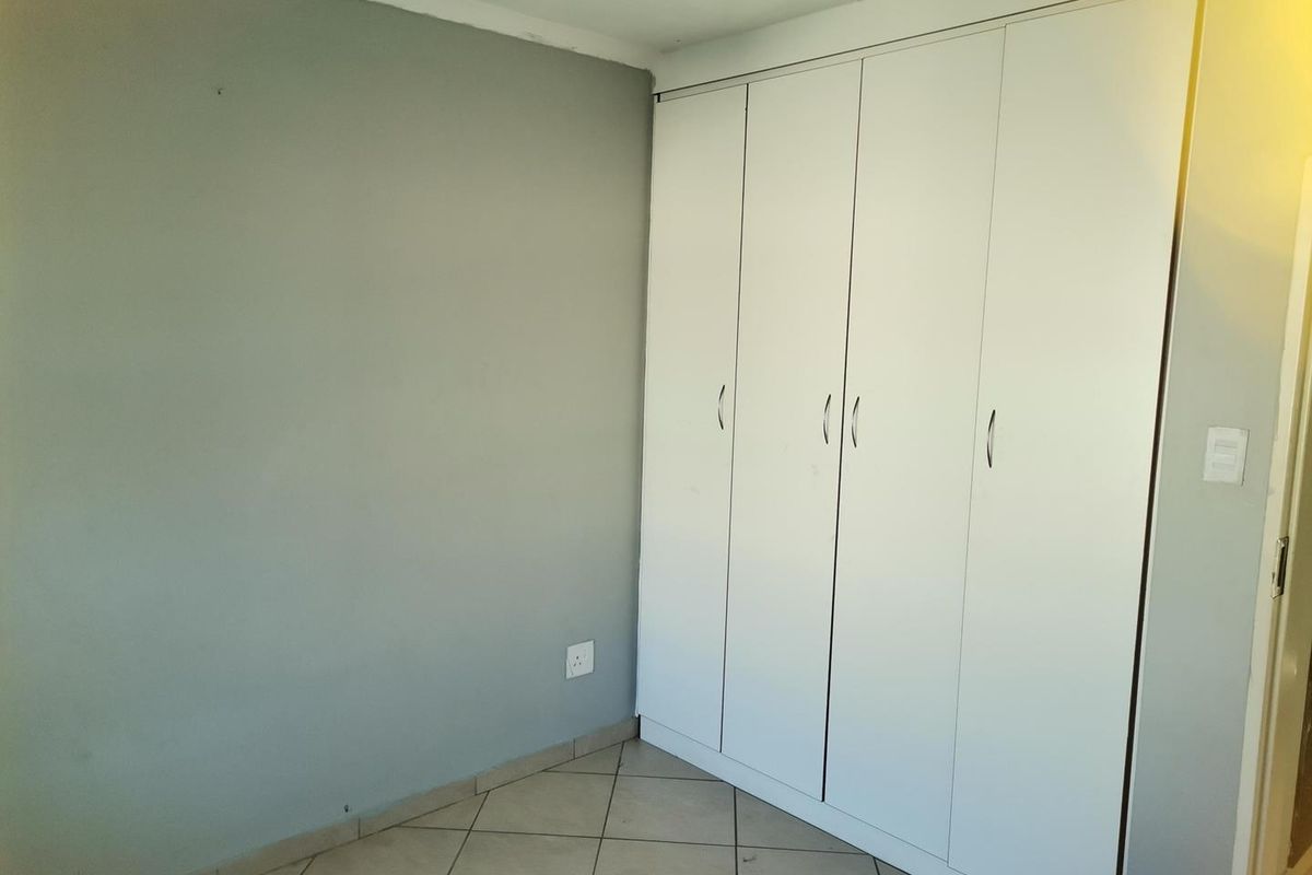 A bedroom featuring built-in white cabinetry and tiled flooring.