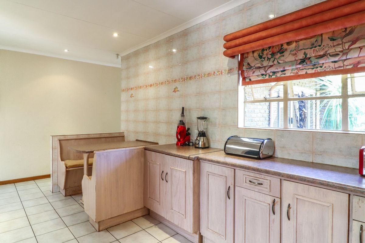 A functional kitchen featuring built-in cabinetry, laminate countertops, a tiled splashback, and a convenient integrated breakfast nook area.