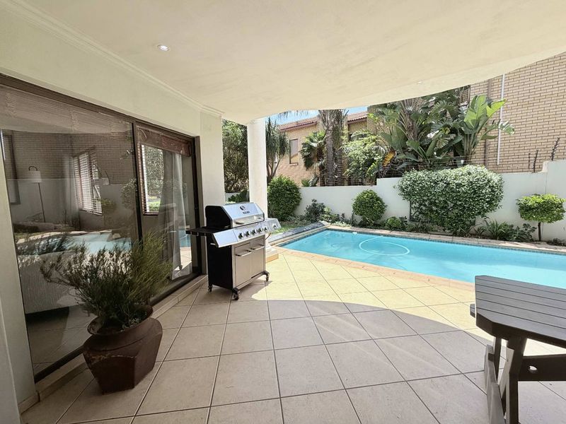 Covered patio area featuring tiled flooring, recessed lighting, and direct access to a private swimming pool and garden space.