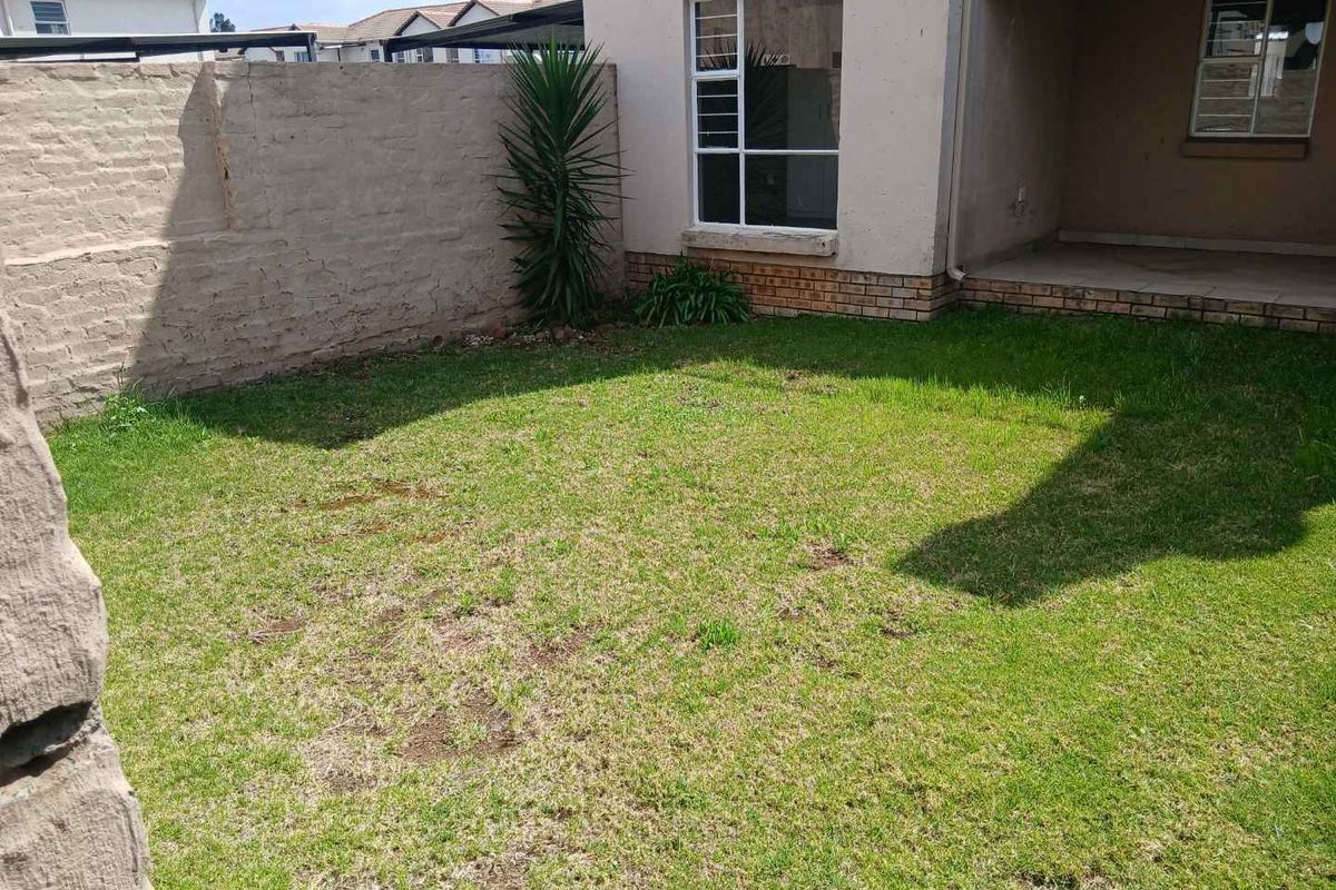 A private rear garden featuring a small lawn area, a paved patio section, and a brick boundary wall.