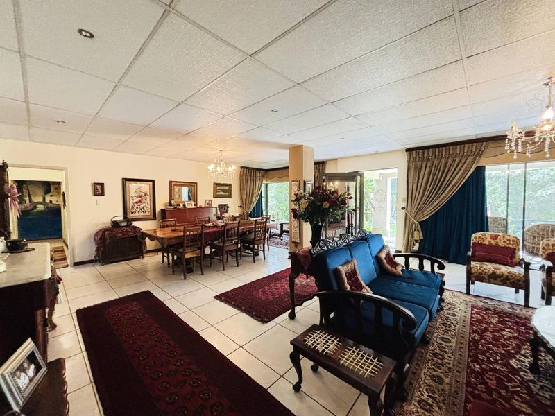 Spacious open-plan living and dining area featuring tiled flooring, a suspended ceiling with recessed lighting, and large sliding glass doors leading to the outdoors.