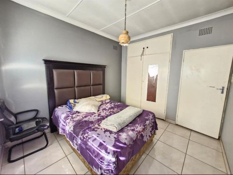 A bedroom featuring tiled flooring, built-in cupboards, and a ceiling light fixture. The room requires cosmetic updates to improve its overall condition.