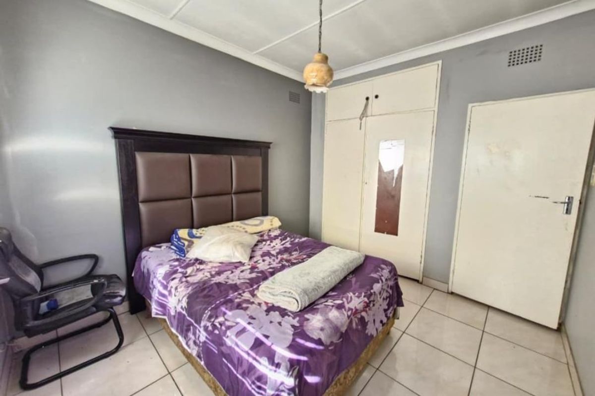 A bedroom featuring tiled flooring, built-in cupboards, and a ceiling light fixture. The room requires cosmetic updates to improve its overall condition.