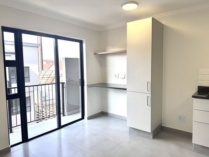 Modern open-plan living area featuring tiled floors, built-in cabinetry, and a sliding glass door providing direct access to a private balcony.