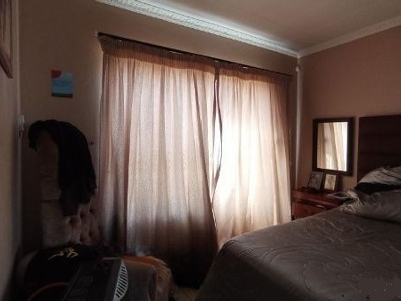 A bedroom featuring crown molding and window treatments, providing a functional space with potential for cosmetic updates.