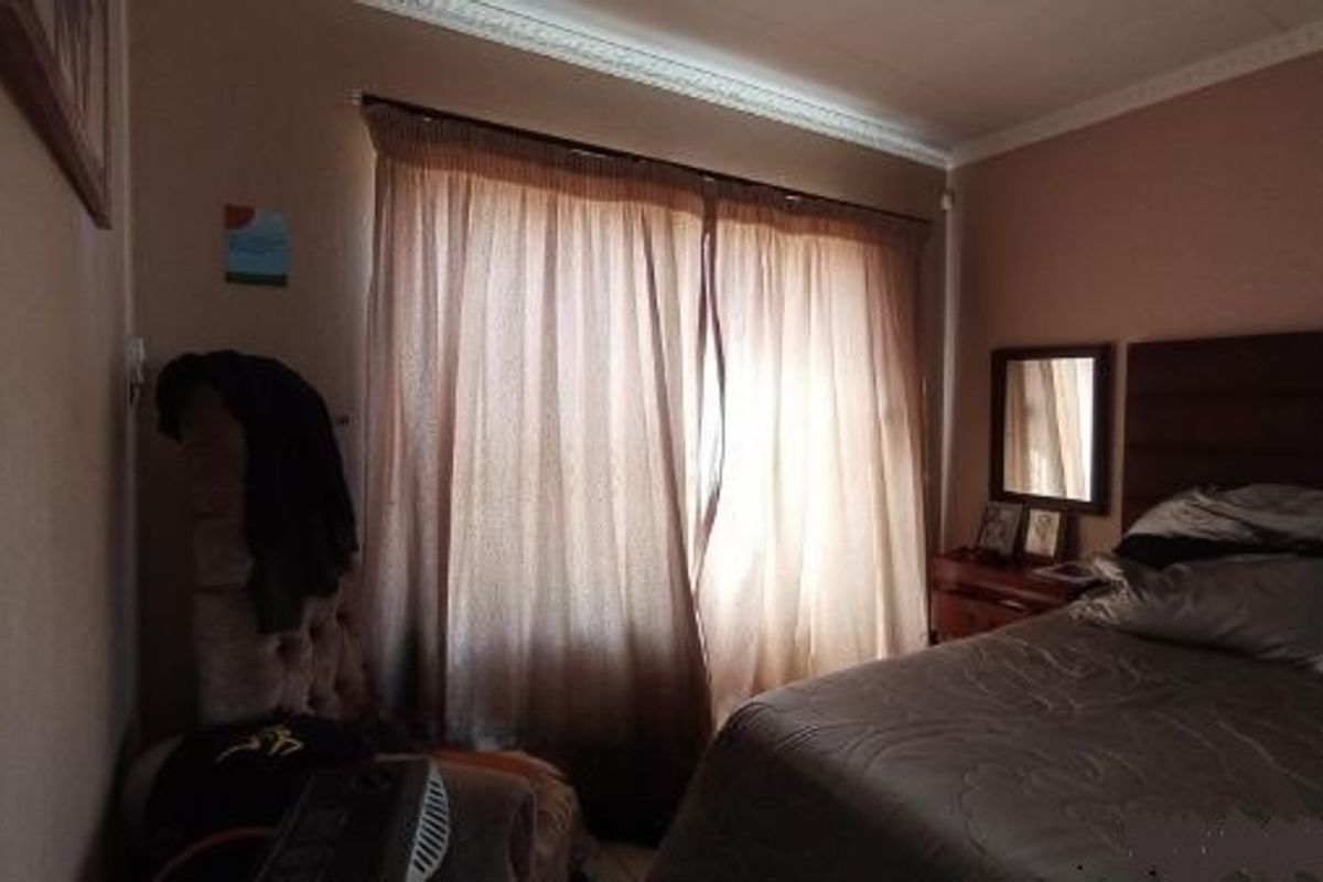 A bedroom featuring crown molding and window treatments, providing a functional space with potential for cosmetic updates.