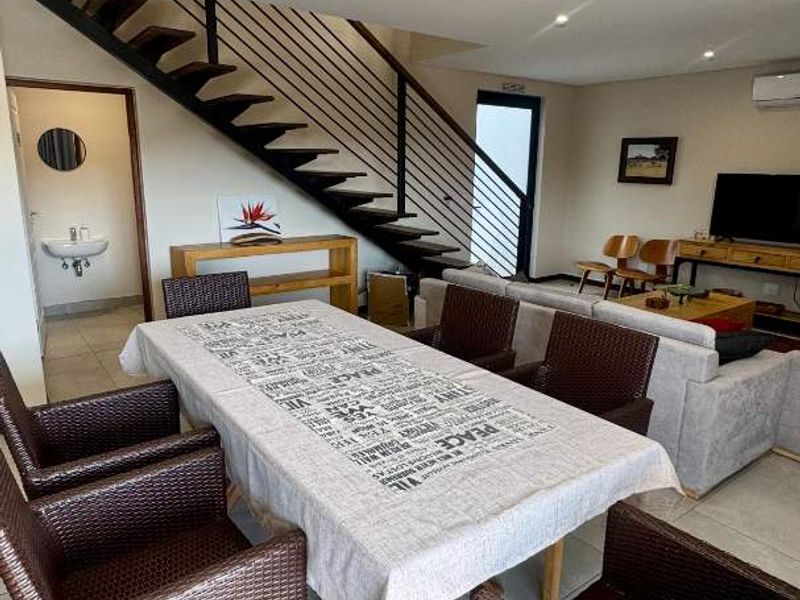Spacious open-plan living and dining area featuring a modern staircase with metal balustrade, tiled flooring, and integrated air conditioning.