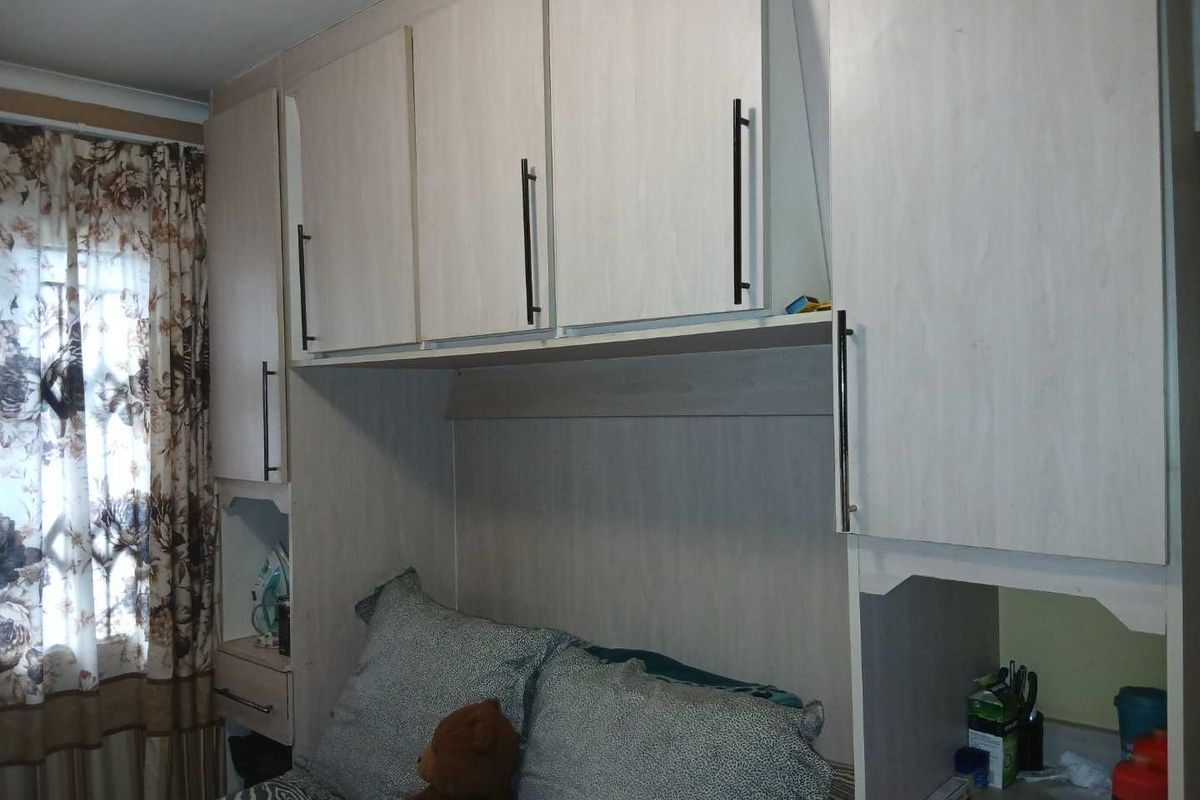 A bedroom featuring built-in cabinetry and overhead storage units surrounding the bed area.