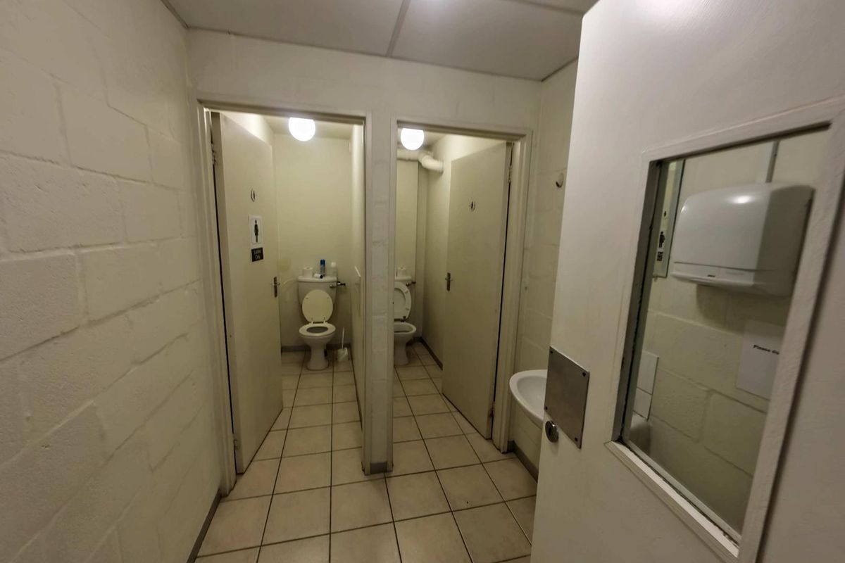 Functional industrial restroom facility featuring two individual toilet cubicles and a shared hand basin area with basic finishes.